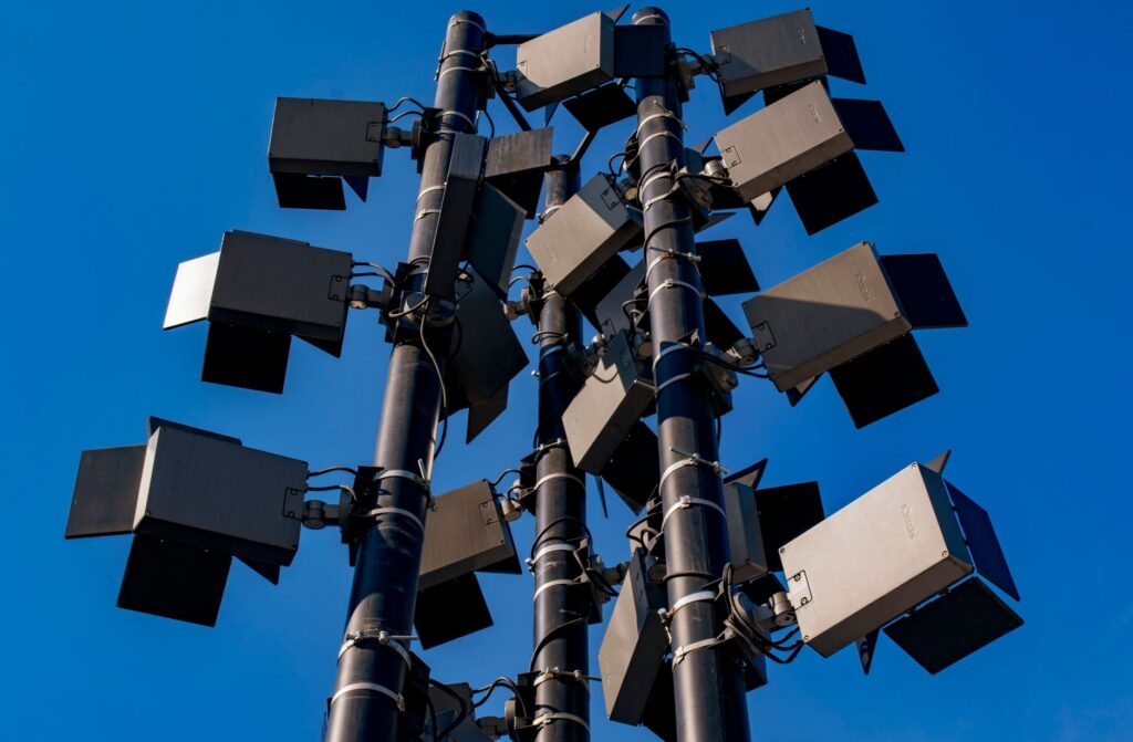 Low angle view of modern outdoor stadium floodlights against a clear blue sky.
