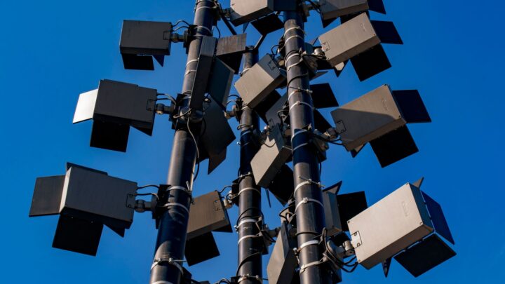 Low angle view of modern outdoor stadium floodlights against a clear blue sky.