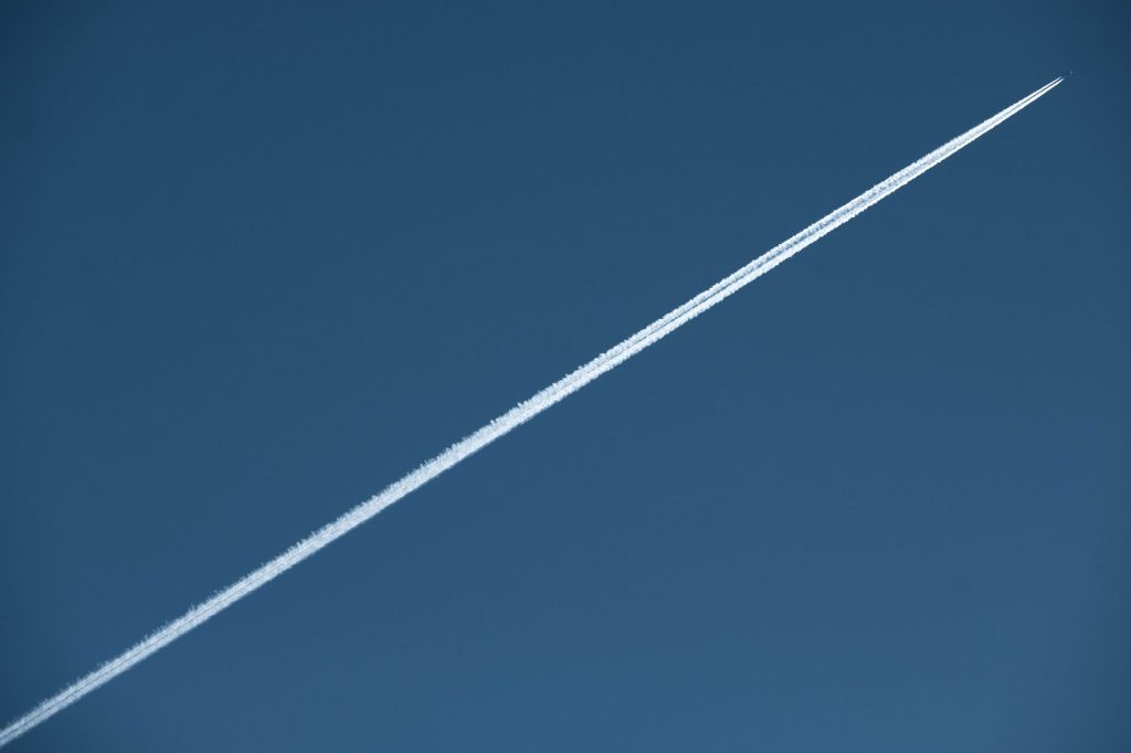 A high-speed jet leaves a distinct contrail in a clear blue sky, showcasing aviation marvel. 文章配图