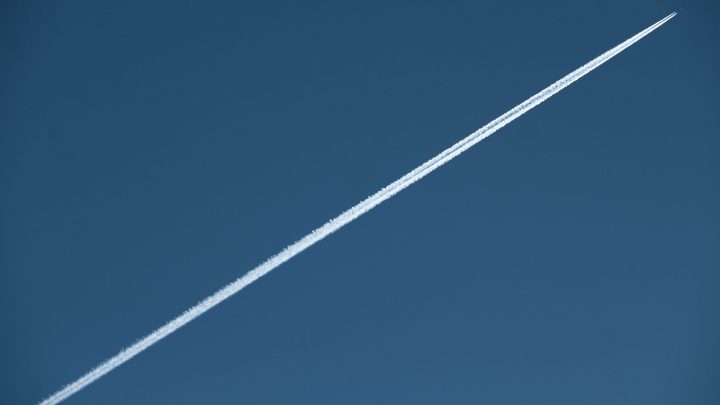 A high-speed jet leaves a distinct contrail in a clear blue sky, showcasing aviation marvel. 文章配图