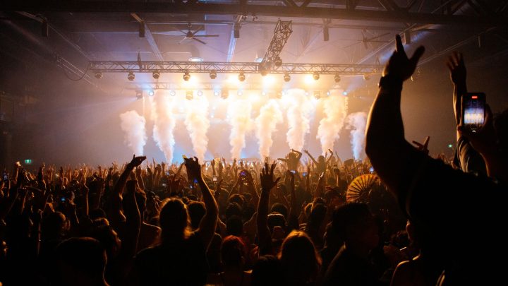 Energetic crowd enjoying a concert with dynamic lighting and smoke effects in an indoor venue. 文章配图