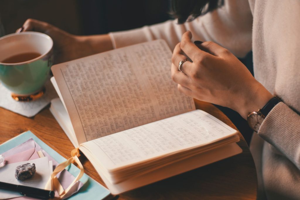 person writing in journal with word boundaries on page