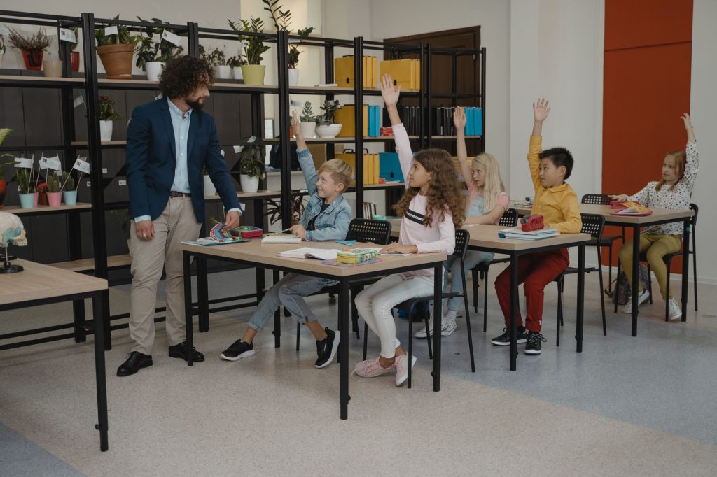 elementary school teacher guiding young students hands-on technology activity