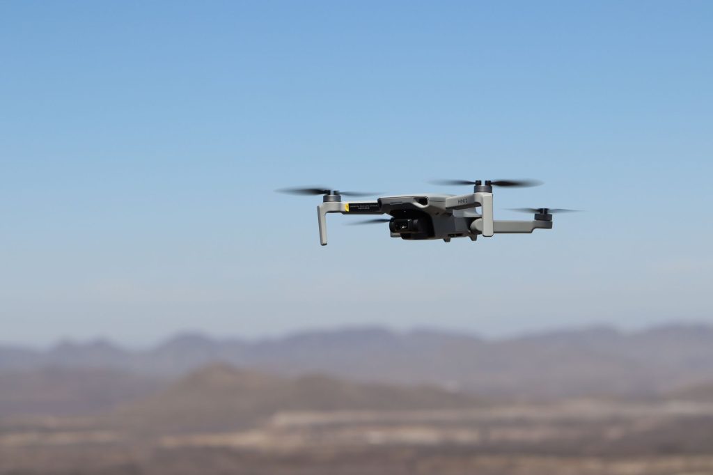 Drone flying over a desert landscape under clear blue skies. 文章配图
