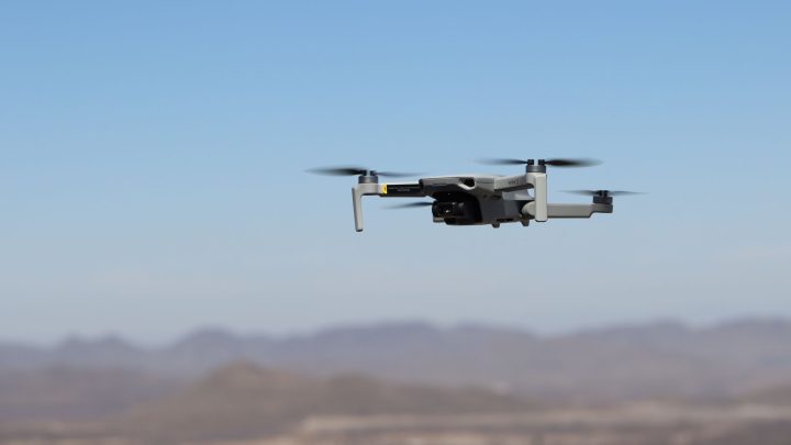 Drone flying over a desert landscape under clear blue skies. 文章配图