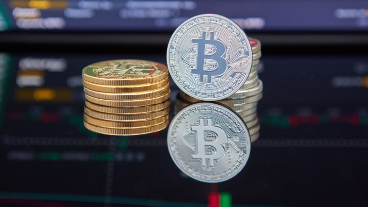 Bitcoin coins stacked in front of cryptocurrency trading chart reflecting market trends.