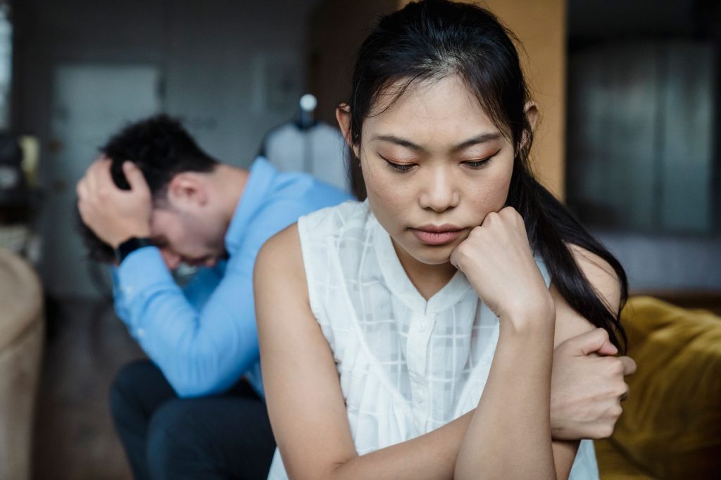 A couple experiencing relationship tension sitting silently on a sofa. 文章配图