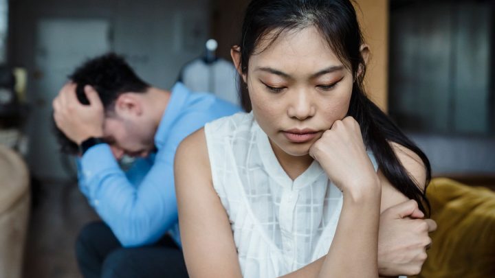 A couple experiencing relationship tension sitting silently on a sofa. 文章配图