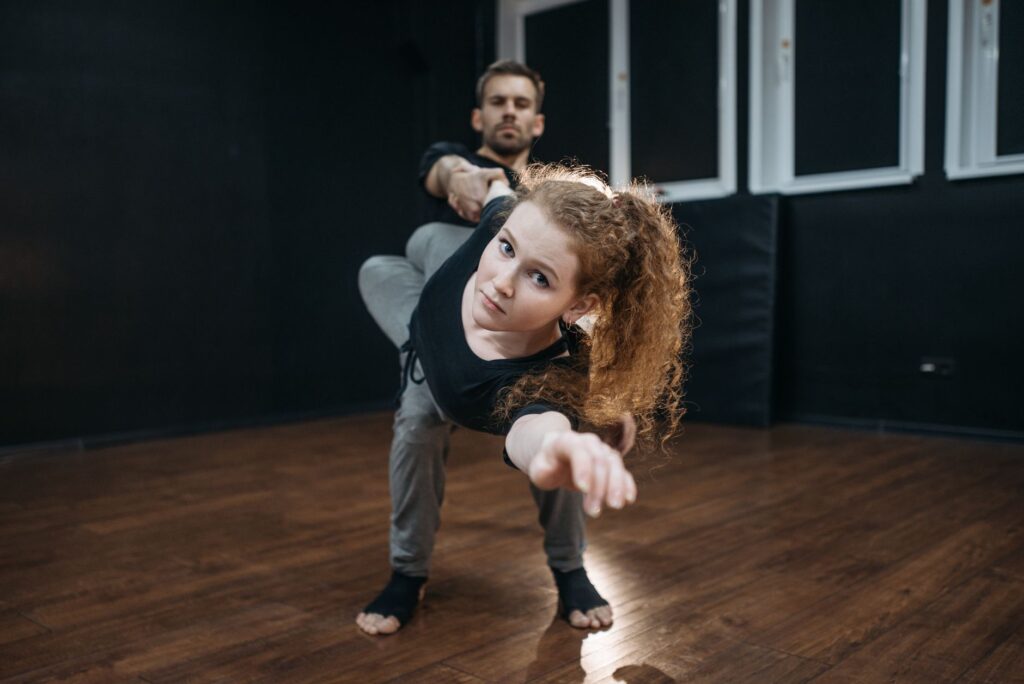 Two dancers perform a captivating move in a dance studio, showcasing their flexibility and strength.